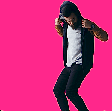 Молодой человек в модной одежде с капюшоном на ярком розовом фоне, позирует в движении.