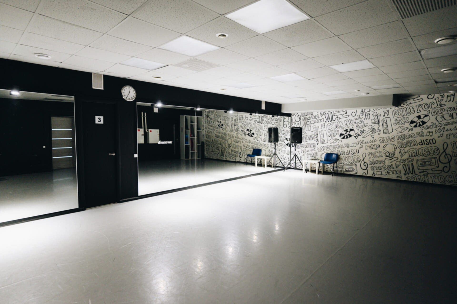 Просторная танцевальная студия с зеркальными стенами и граффити, готовая для занятий хореографией.