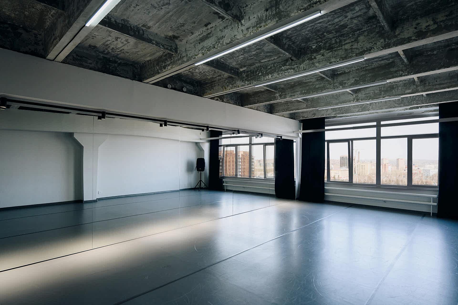 Современная светлая студия с зеркалами и панорамными окнами в индустриальном стиле.