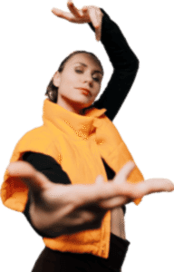 Танцовщица в ярко-оранжевой куртке исполняет современное движение, с вытянутыми руками на фоне белого пространства.